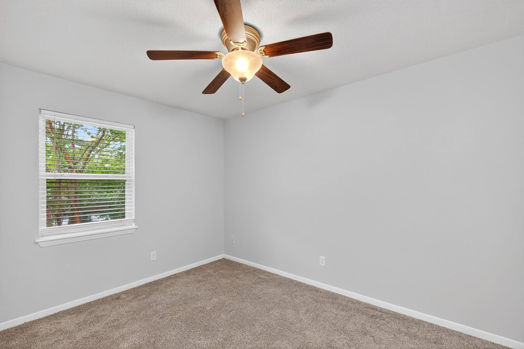 A room with a ceiling fan and a window at The Landing Townhomes Apartments, Hanahan, SC