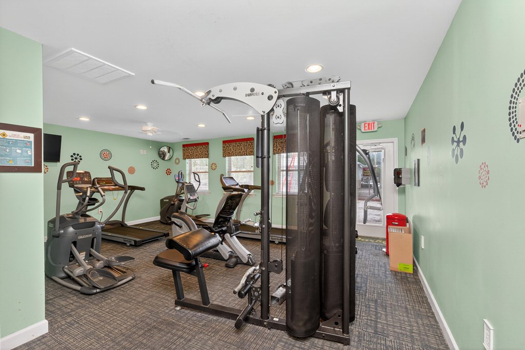 A gym with a variety of equipment including treadmills, weights, and a squat rack at Woodlocke Apartments, Moncks Corner, SC