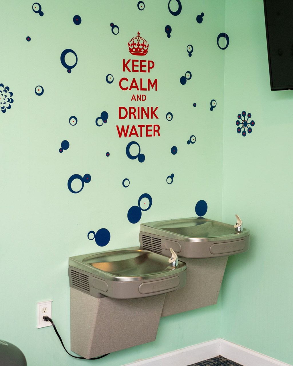 Two sinks under a sign that says keep calm and drink water at Woodlocke Apartments, Moncks Corner, SC, 27461