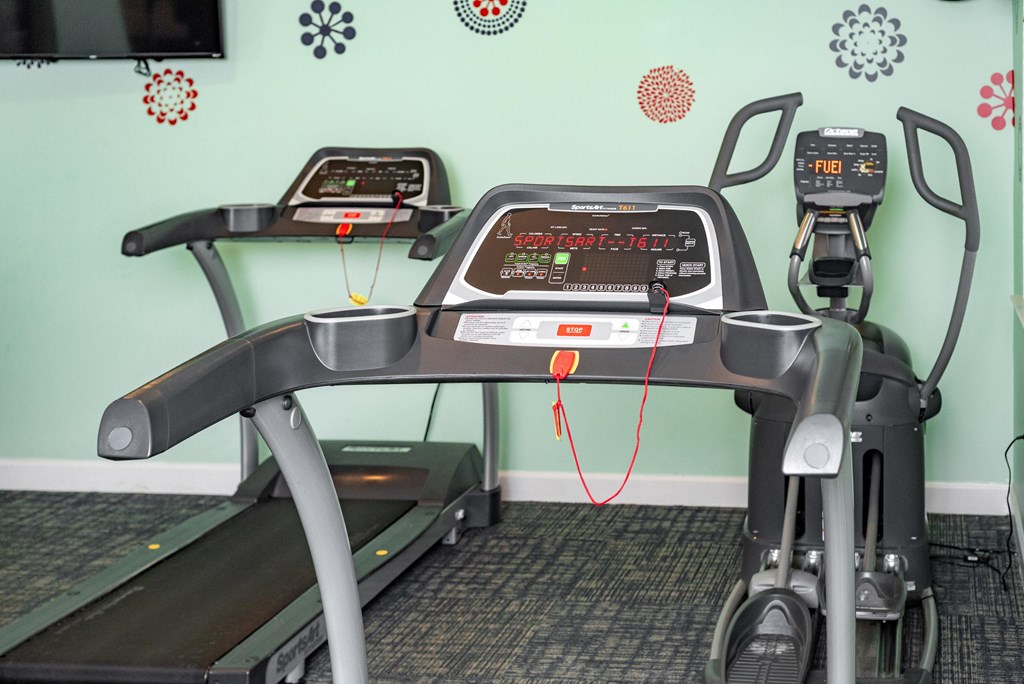 A treadmill and a stationary bike are in a room with green walls at Woodlocke Apartments, Moncks Corner