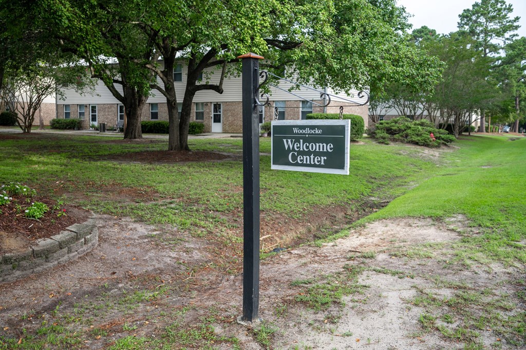 A sign that says Welcome Center stands in front of a building at Woodlocke Apartments, South Carolina, 27461