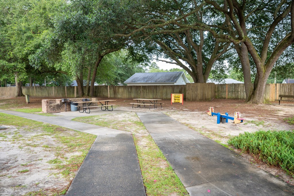 A park with a paved walkway, picnic tables, and a playground at Woodlocke Apartments, Moncks Corner, South Carolina