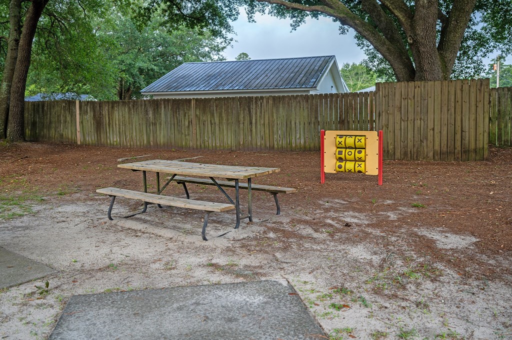 A picnic table is in front of a fence with a sign on it at Woodlocke Apartments, Moncks Corner, SC