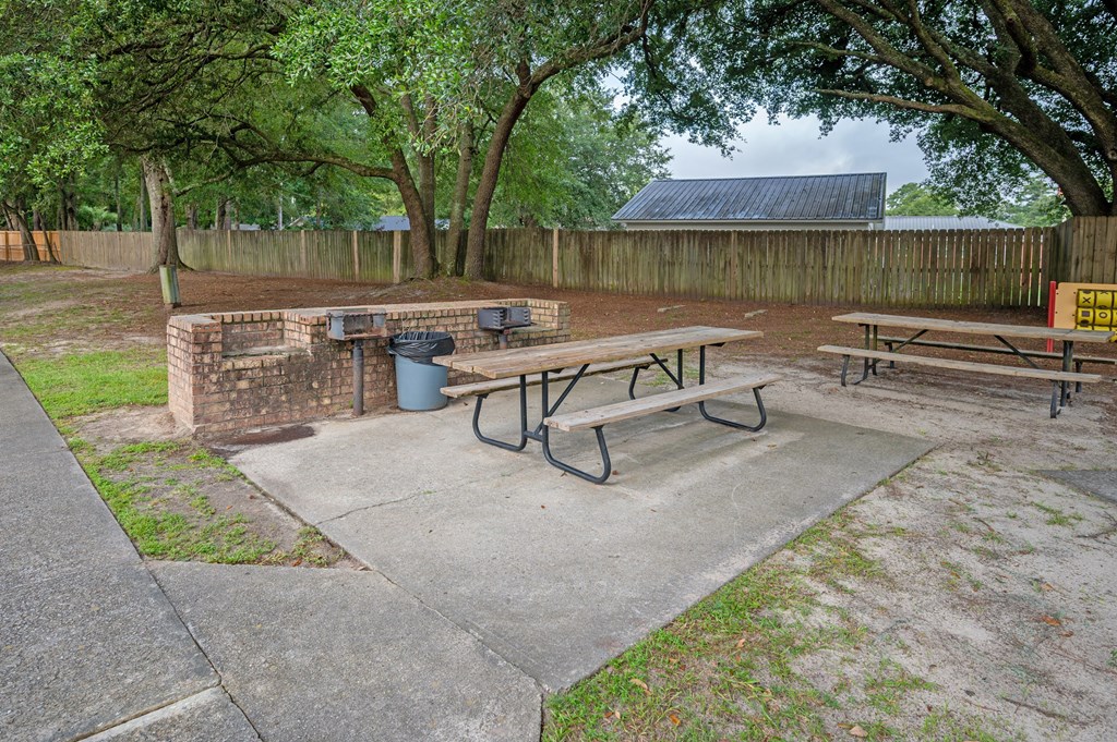 A picnic area with a table and benches surrounded by trees at Woodlocke Apartments, South Carolina