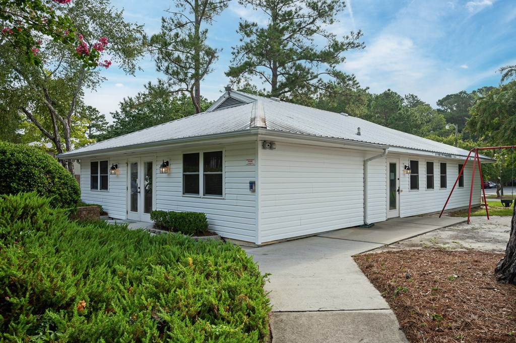 A white building with a grey roof surrounded by greenery at Woodlocke Apartments, Moncks Corner