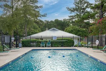 A pool with a blue sign in the background. at Woodlocke Apartments, Moncks Corner, SC, 27461