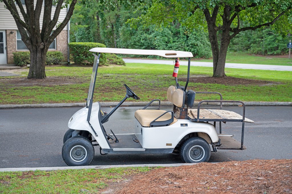 A white golf cart is parked on the side of a road at Woodlocke Apartments, South Carolina, 27461