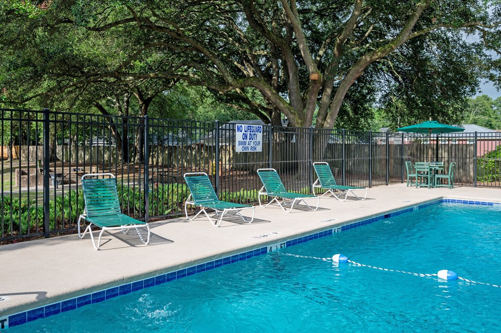 A pool with chairs and a sign on a fence at Woodlocke Apartments, Moncks Corner, SC