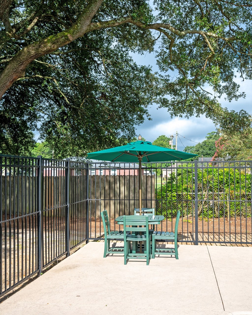 A green umbrella is behind a green table and chairs at Woodlocke Apartments, Moncks Corner