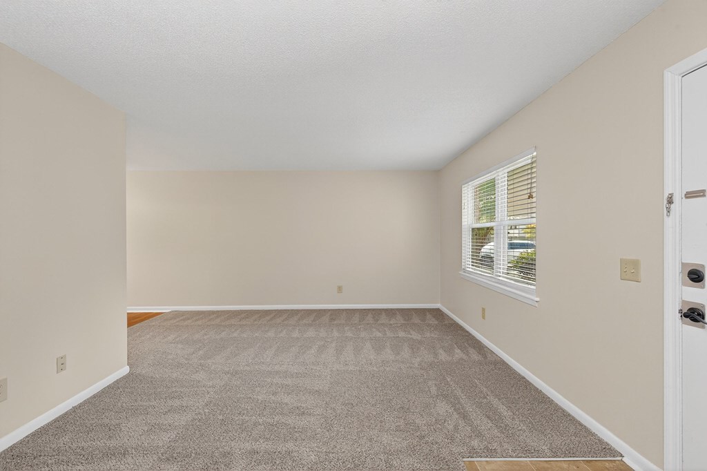 A room with a carpeted floor and a window with blinds at Woodlocke Apartments, South Carolina, 27461