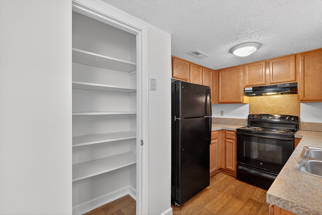 A kitchen with a black refrigerator and wooden cabinets at Woodlocke Apartments, South Carolina, 27461