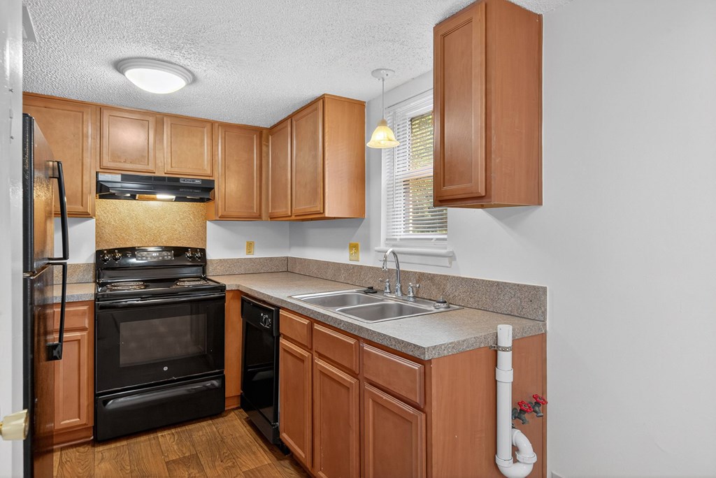 A kitchen with wooden cabinets and a black stove top oven at Woodlocke Apartments, Moncks Corner 27461