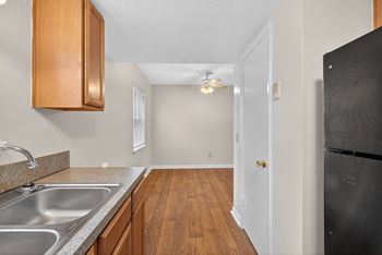 A kitchen with wooden cabinets and a black refrigerator. at Woodlocke Apartments, Moncks Corner, SC