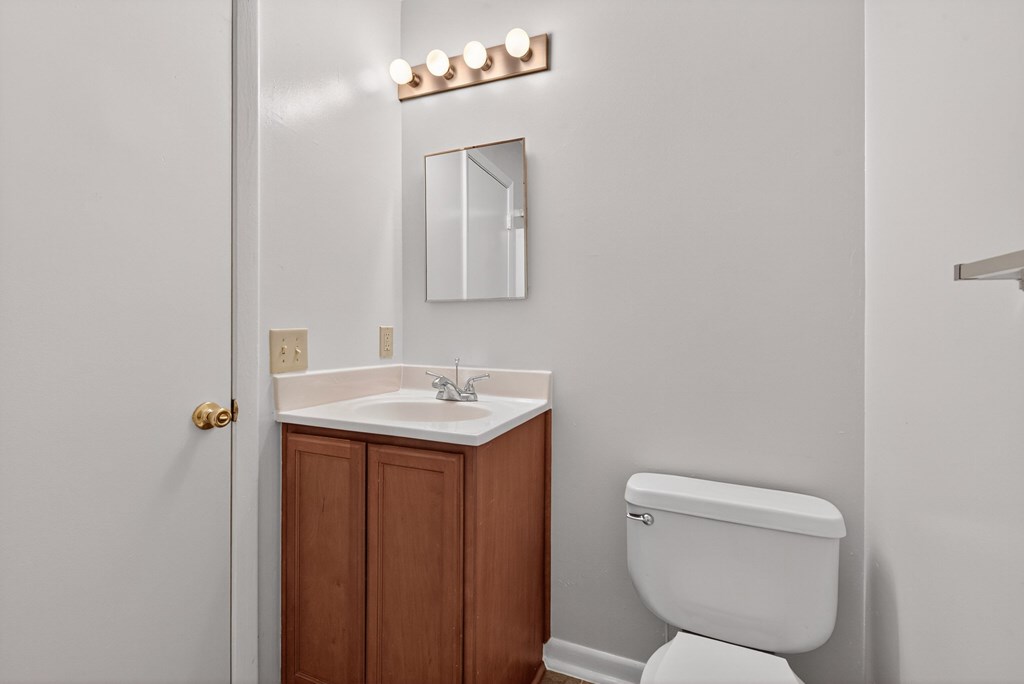 A white toilet sits next to a sink in a bathroom at Woodlocke Apartments, Moncks Corner, SC, 27461