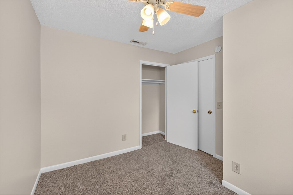 A room with a ceiling fan and carpeted floor at Woodlocke Apartments, Moncks Corner 27461