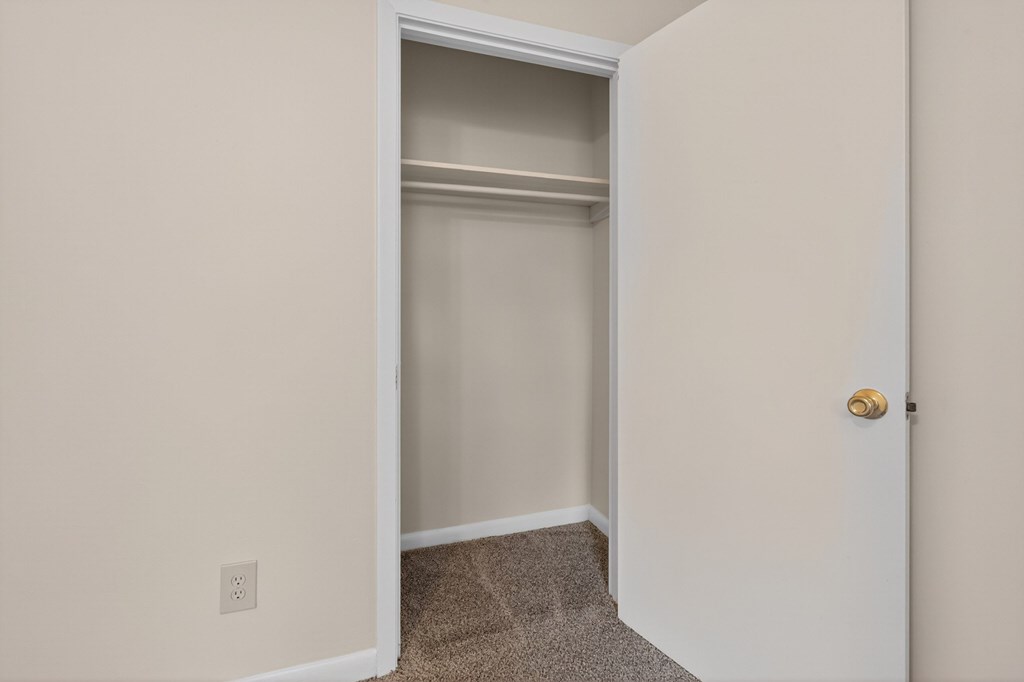 A white door with a gold handle is open to a carpeted hallway at Woodlocke Apartments, Moncks Corner