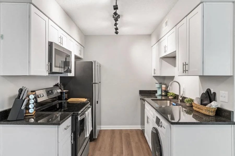 A kitchen with white cabinets and black appliances.