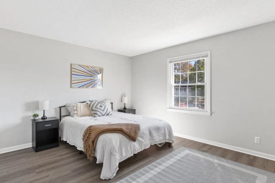 A bedroom with a bed, nightstands, and a window.