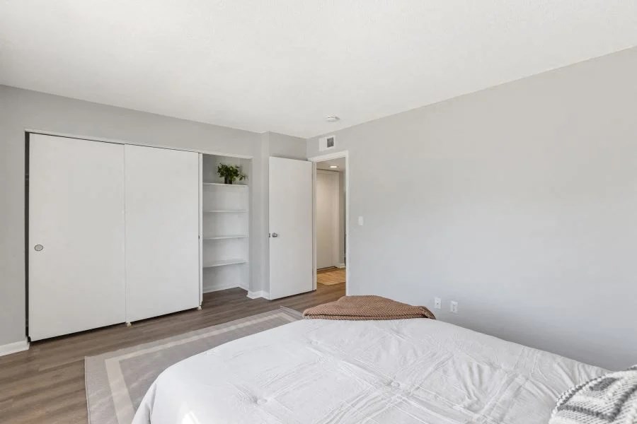 A white bed with a white comforter in a room with white walls at The Preserve at Pine Valley Apartments, Wilmington, North Carolina