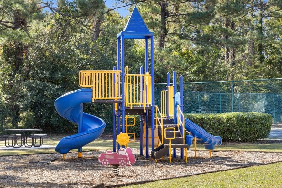 A playground with a blue and yellow slide and a pink car at The Preserve at Pine Valley Apartments, Wilmington