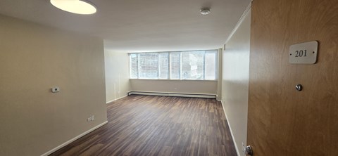 A room with wooden floors and a window with blinds.