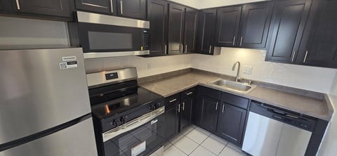 A kitchen with black cabinets and stainless steel appliances.