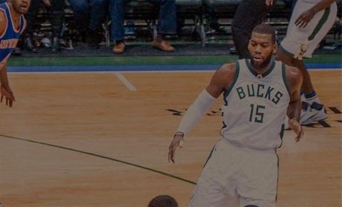 A basketball player in a Bucks jersey is dribbling the ball.
