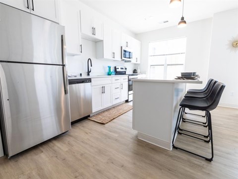 A modern kitchen with a stainless steel refrigerator and a black chair.