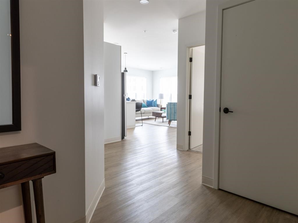 A hallway with a wooden floor and white walls.
