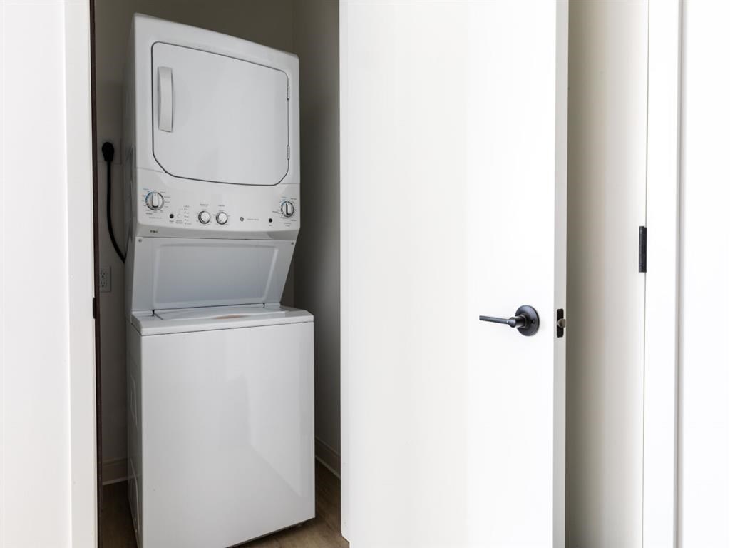 A white dishwasher is in a narrow space between a door and a wall.