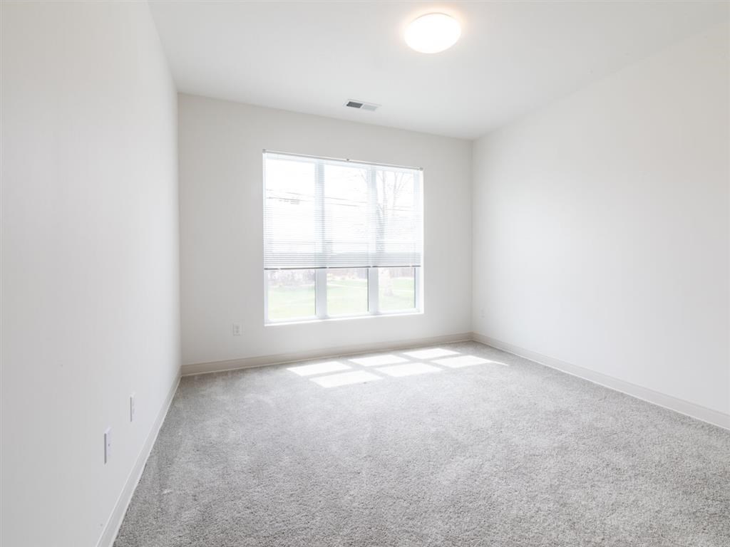 A spacious room with a large window and carpeted floor.