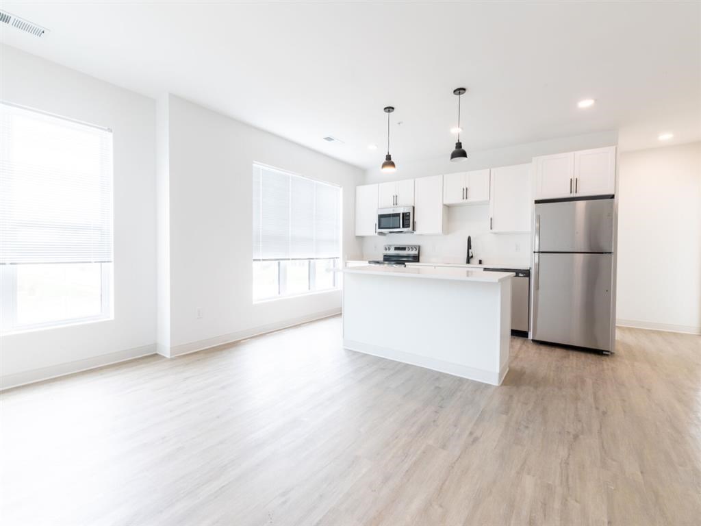 A modern kitchen with a white countertop and stainless steel appliances.