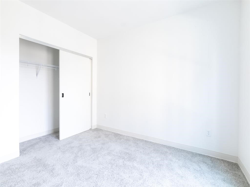 A white room with a carpeted floor and a white door.