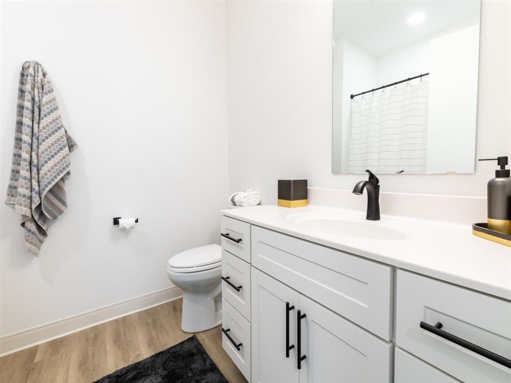 A white bathroom with a toilet, sink, and mirror.