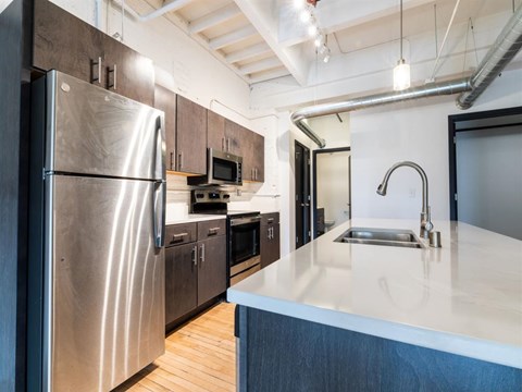 A modern kitchen with a stainless steel refrigerator and a white countertop.