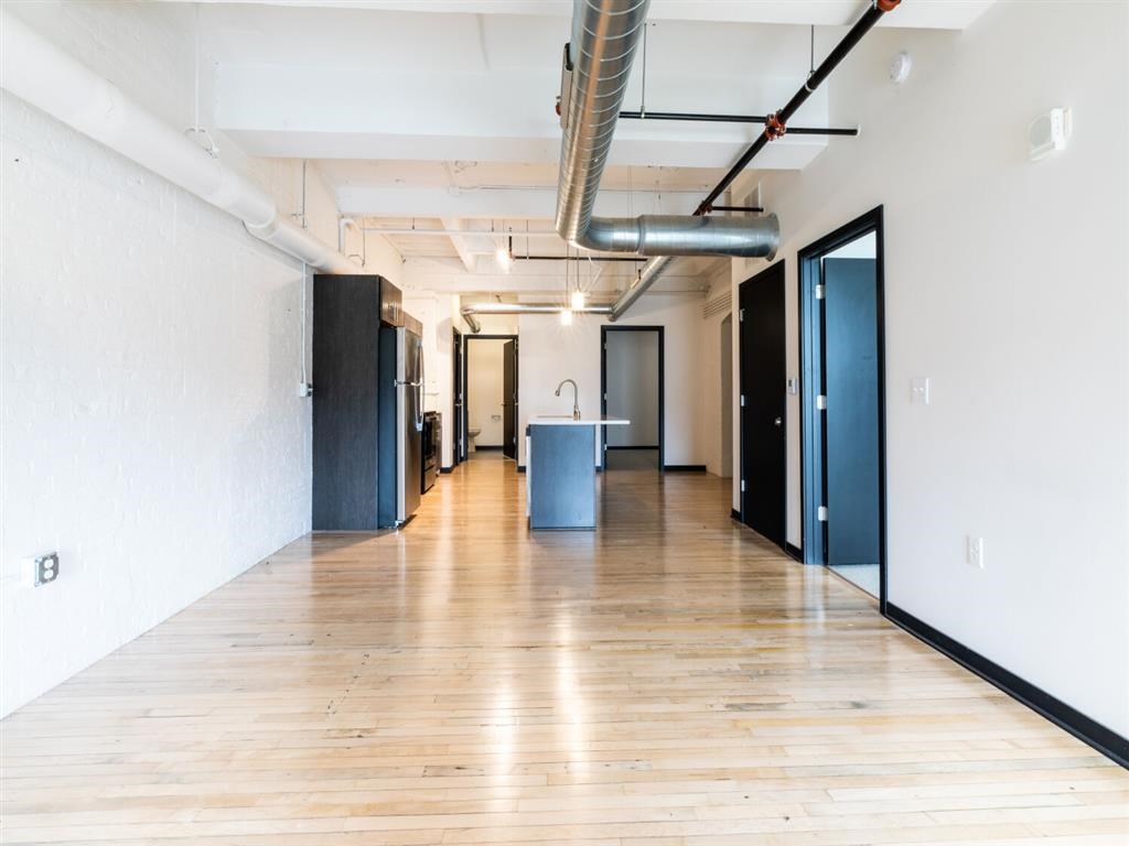 A long hallway with doors on both sides and a trash can in the middle.