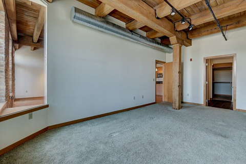A room with a carpeted floor and a wooden beam ceiling.