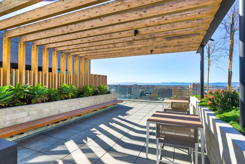 A wooden patio with chairs and a table with a view of the city.at Eleven Fifty Clay Street, Oakland  