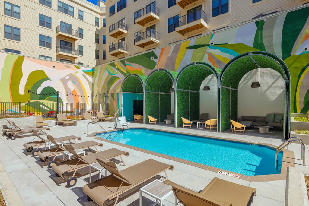A pool surrounded by sun loungers and a building with a mural on the side. A pool surrounded by sun loungers and a building with a mural on the side.at The Vale at the Parks, Washington, 20012