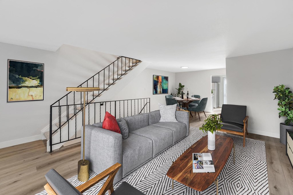A living room with a grey couch, a coffee table, and a staircase. at The Lex At Lowry, Denver, CO, 80224