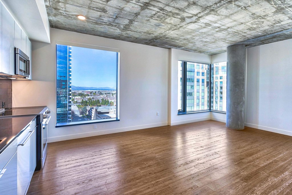 A spacious room with wooden floors and a large window overlooking a cityscape.at Eleven Fifty Clay Street, Oakland, 94607  