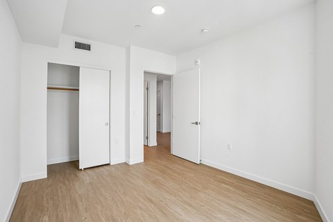 A white room with wood flooring and a few doors.