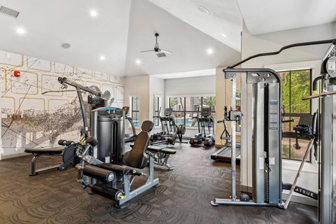A gym with a variety of equipment including a weight bench, a leg press machine, and a cable machine.