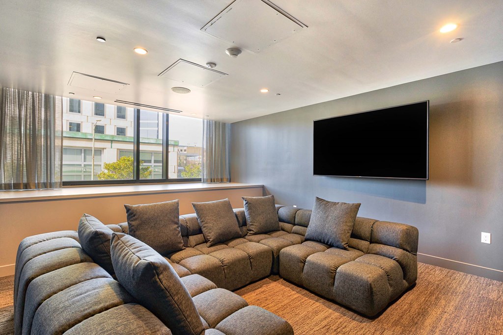 A living room with a large sectional sofa and a flat screen TV mounted on the wall.at Eleven Fifty Clay Street, Oakland, CA 94607  