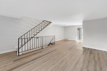 A wooden staircase with a metal railing leads to a second floor. at The Lex At Lowry, Denver, 80224