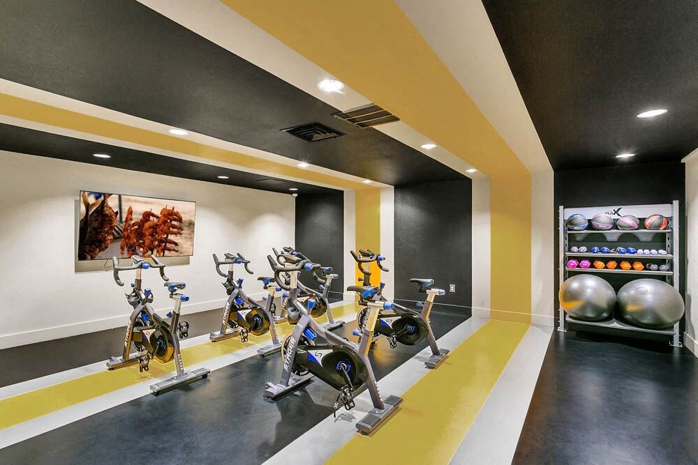 A gym with exercise bikes and a shelf of exercise balls. at The Lex At Lowry, Denver, 80224