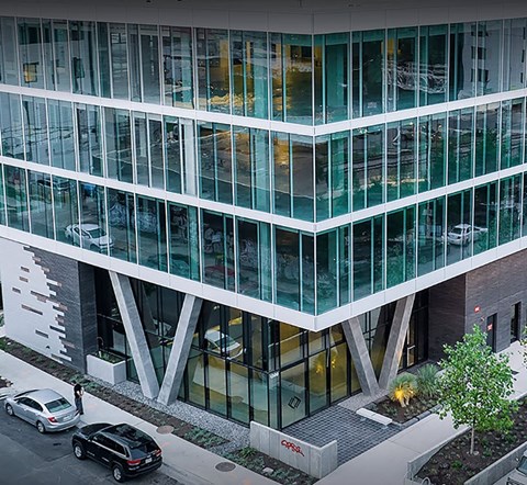 A modern building with glass windows and a tree in front.