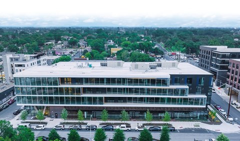 A large glass building with a parking lot in front.