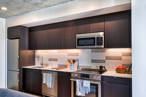 A modern kitchen with dark wood cabinets and stainless steel appliances. A modern kitchen with dark wood cabinets and stainless steel appliances.at Eleven Fifty Clay Street, Oakland