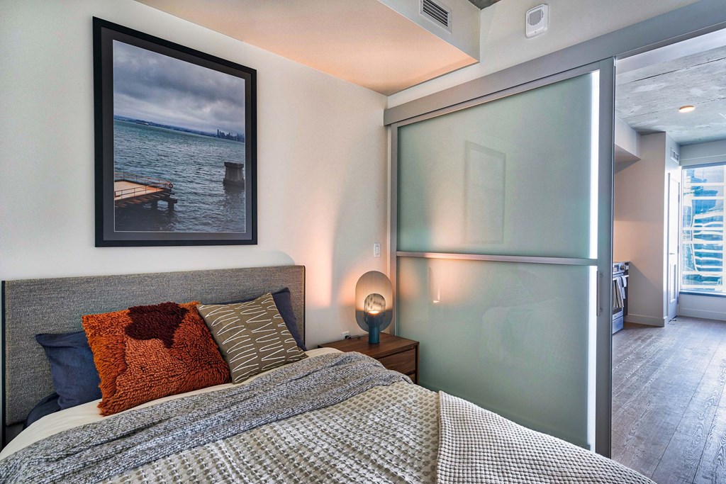 A bedroom with a bed, nightstand, and a picture on the wall.at Eleven Fifty Clay Street, Oakland, CA  